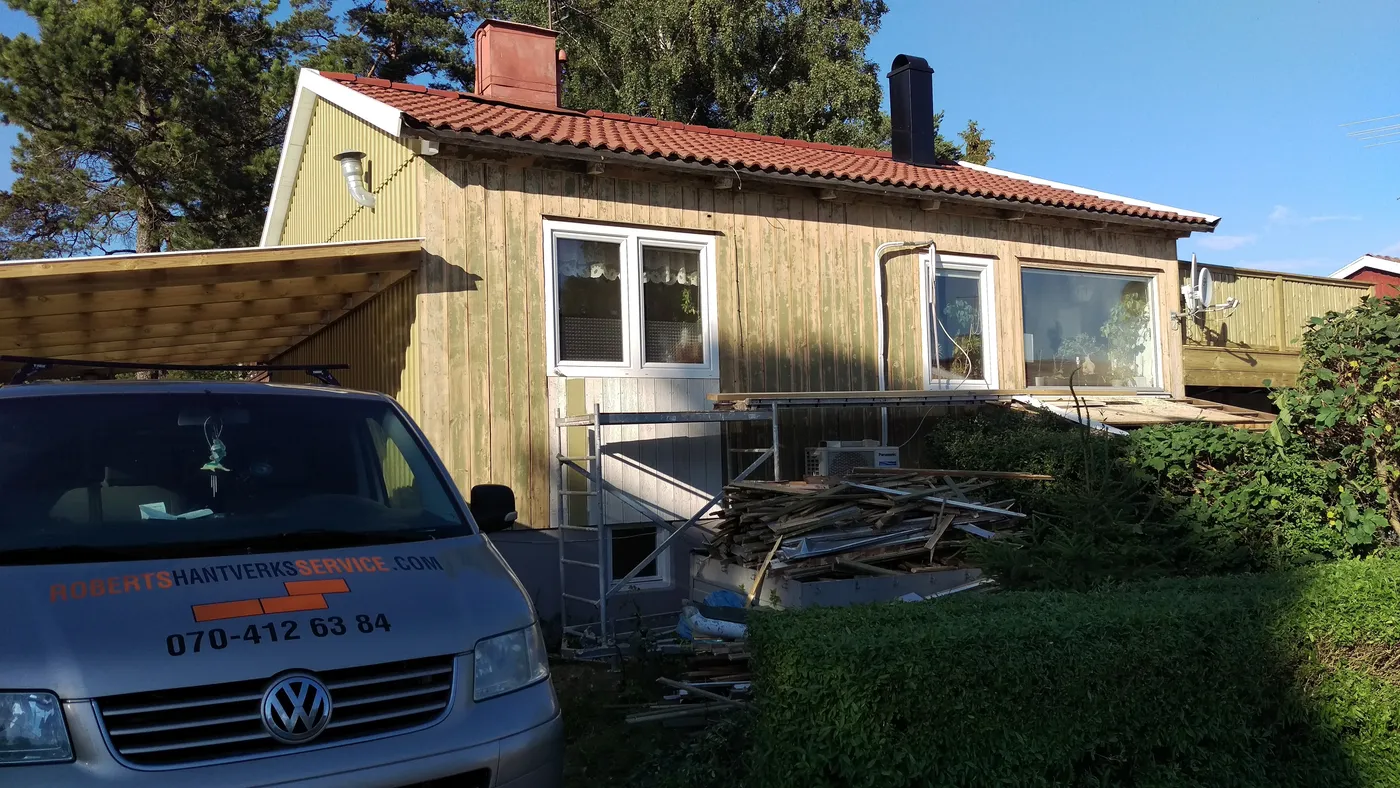 Fasaden fräst ner till rent trä, med carport och firmabil på uppfarten